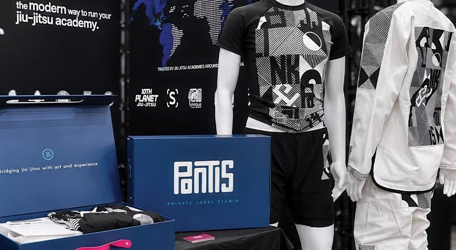 The BJJLink booth at Jiu-Jitsu Con: Pontis Private Label Studio box open on the table, Span 01 rash guard and Kimono on mannequins